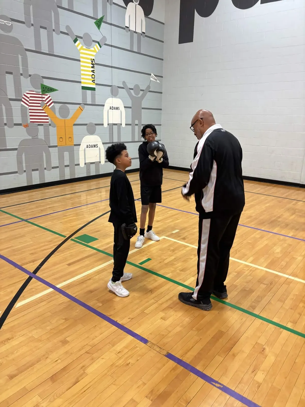 A coach giving instruction to two young boxers